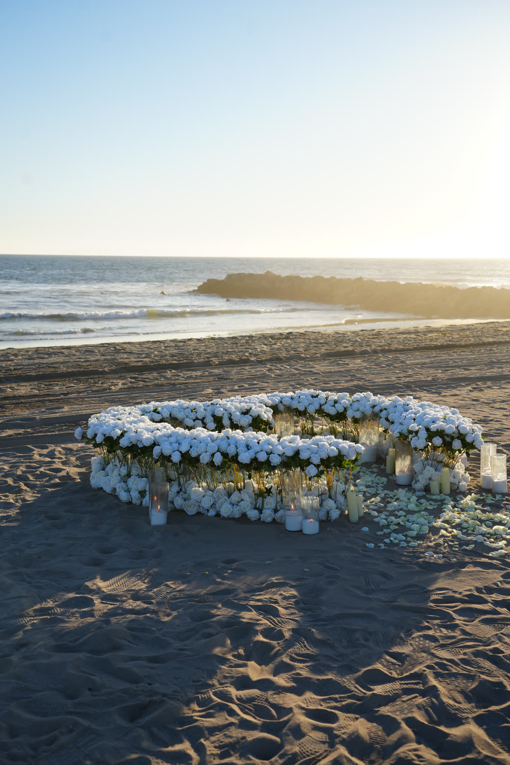 Large white heart created with 800 artificial roses on the beach